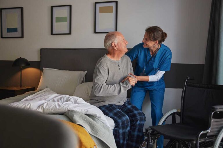 A senior boarding a wheelchair-accessible van with the help of an attendant in a residential setting.