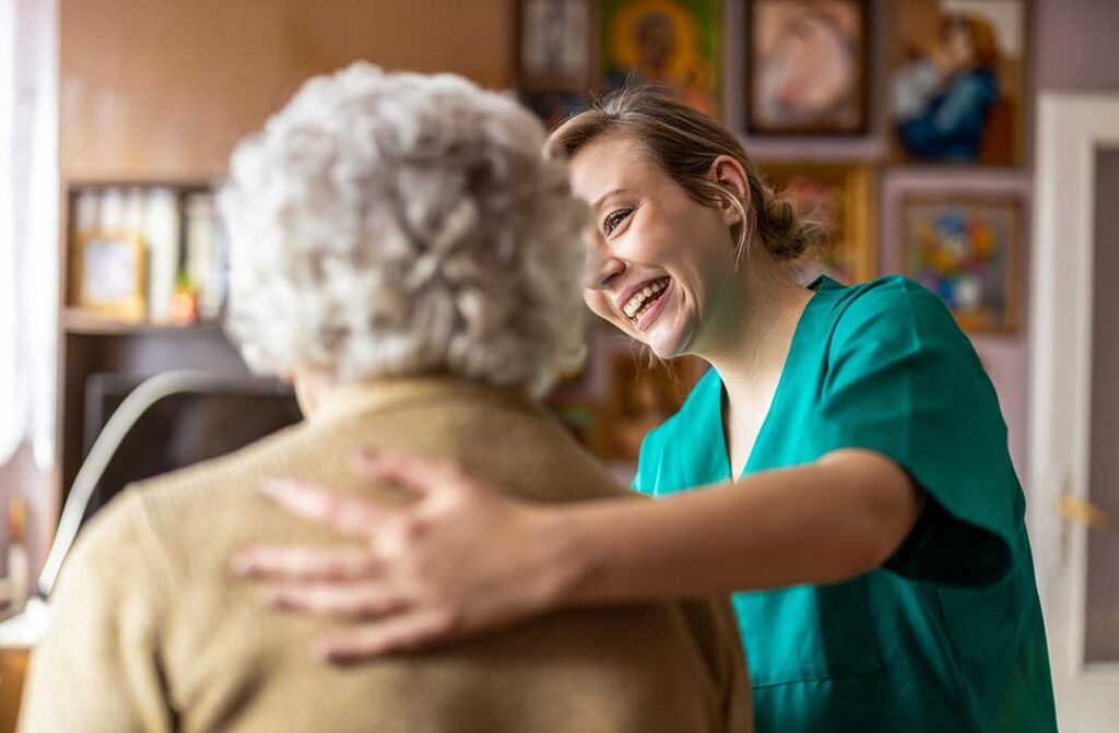 Two senior residents receiving medication from a caregiver in a comfortable, home-like common room.